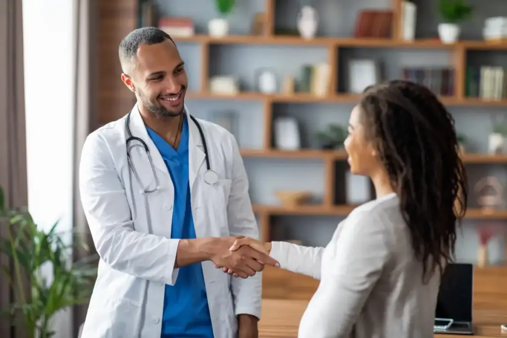 Jovem médico cumprimentando paciente com aperto de mãos